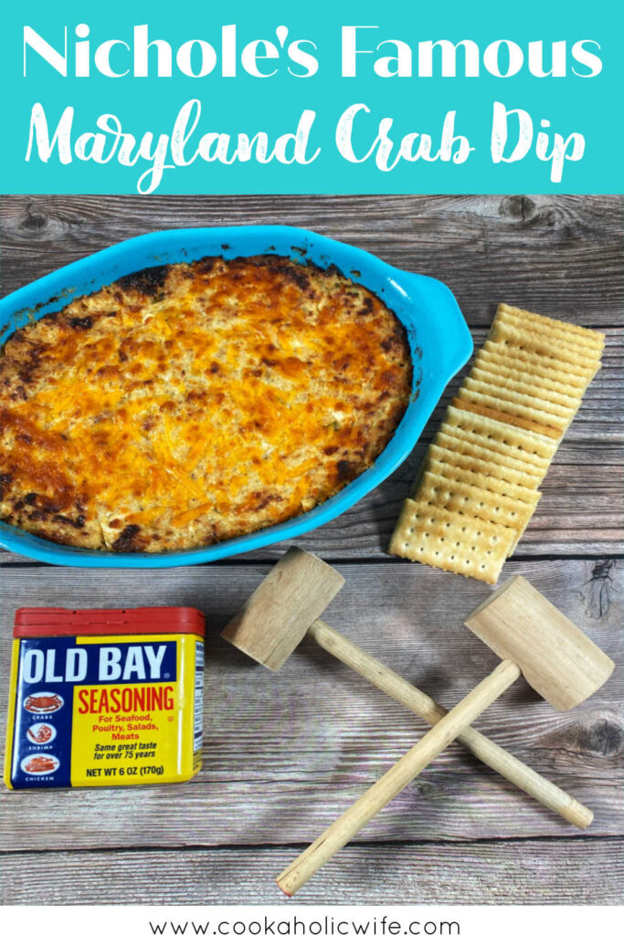 image for pinterest with recipe title text overlay at top. Dish of crab dip sits on a wooden background, with crackers, Old Bay seasoning and crab mallets in the foreground. 