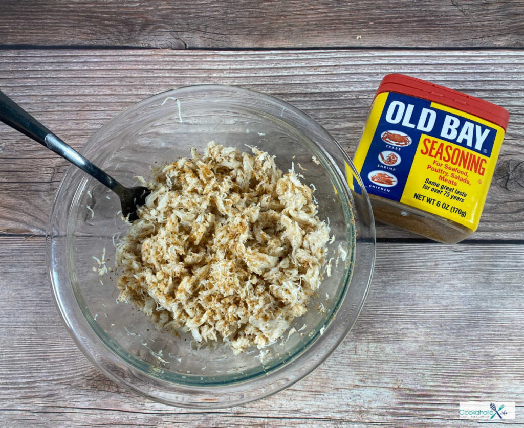 process shot, crab meat sits in a glass bowl seasoned with Old Bay. 