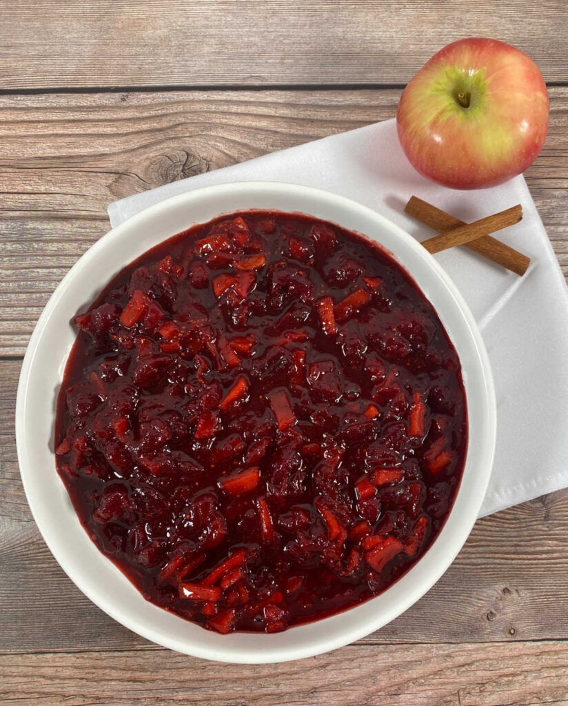 cranberry sauce sits on a wooden background in a shallow white dish. 