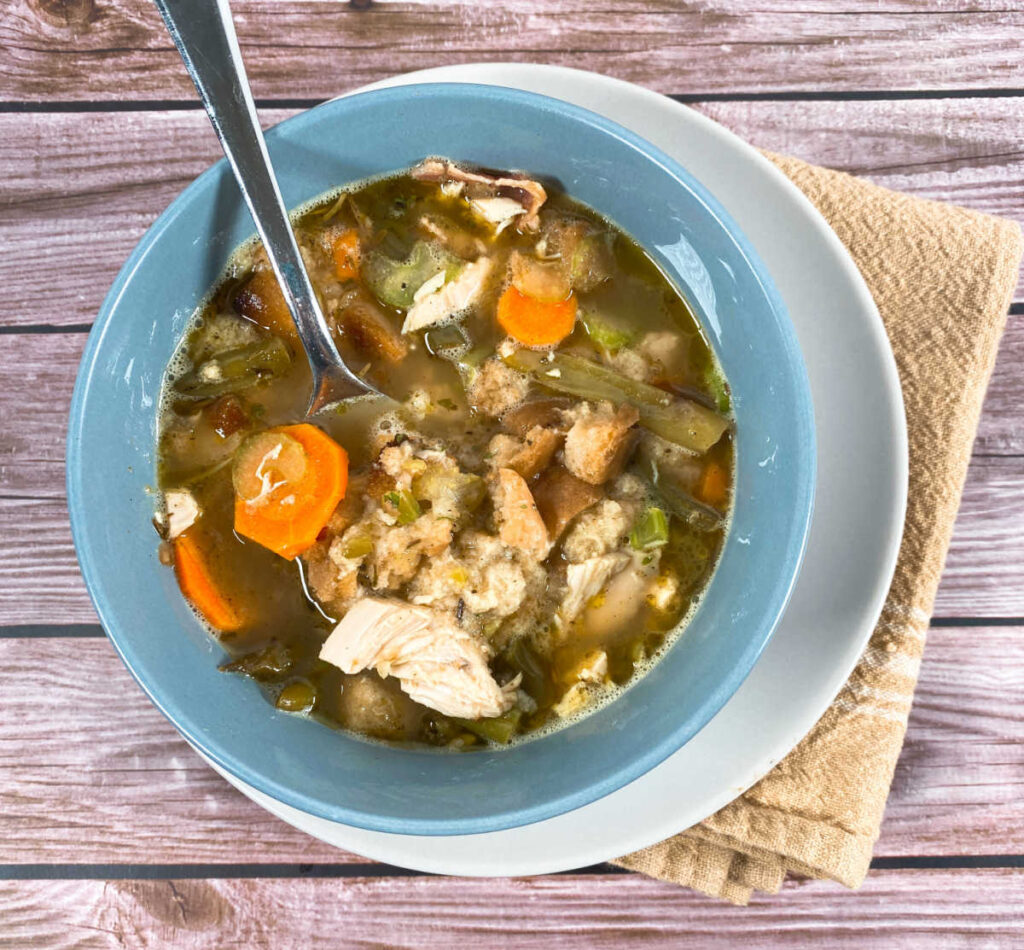 Blue bowl of Leftover Turkey Dumpling Soup sits on a wooden background. 