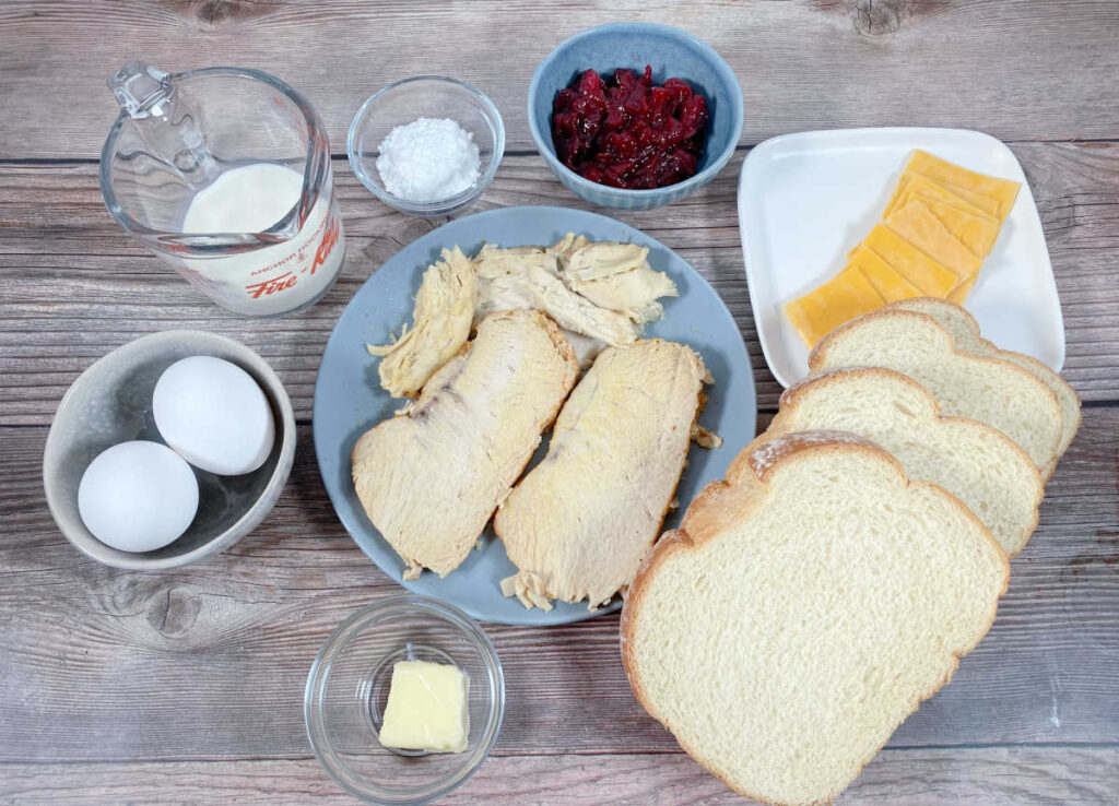 ingredients for the sandwich sit on a wooden background.