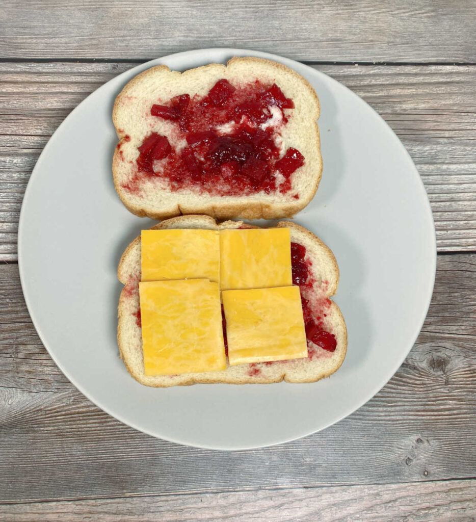 Process shot- two slices of bread, cranberry sauce spread on each, cheese on top. 
