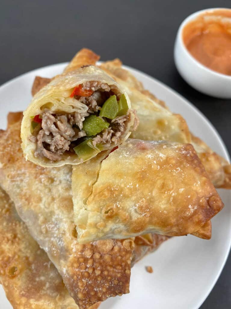 Close up of halved egg roll to show the filling sits on a pyramid of other egg rolls. 