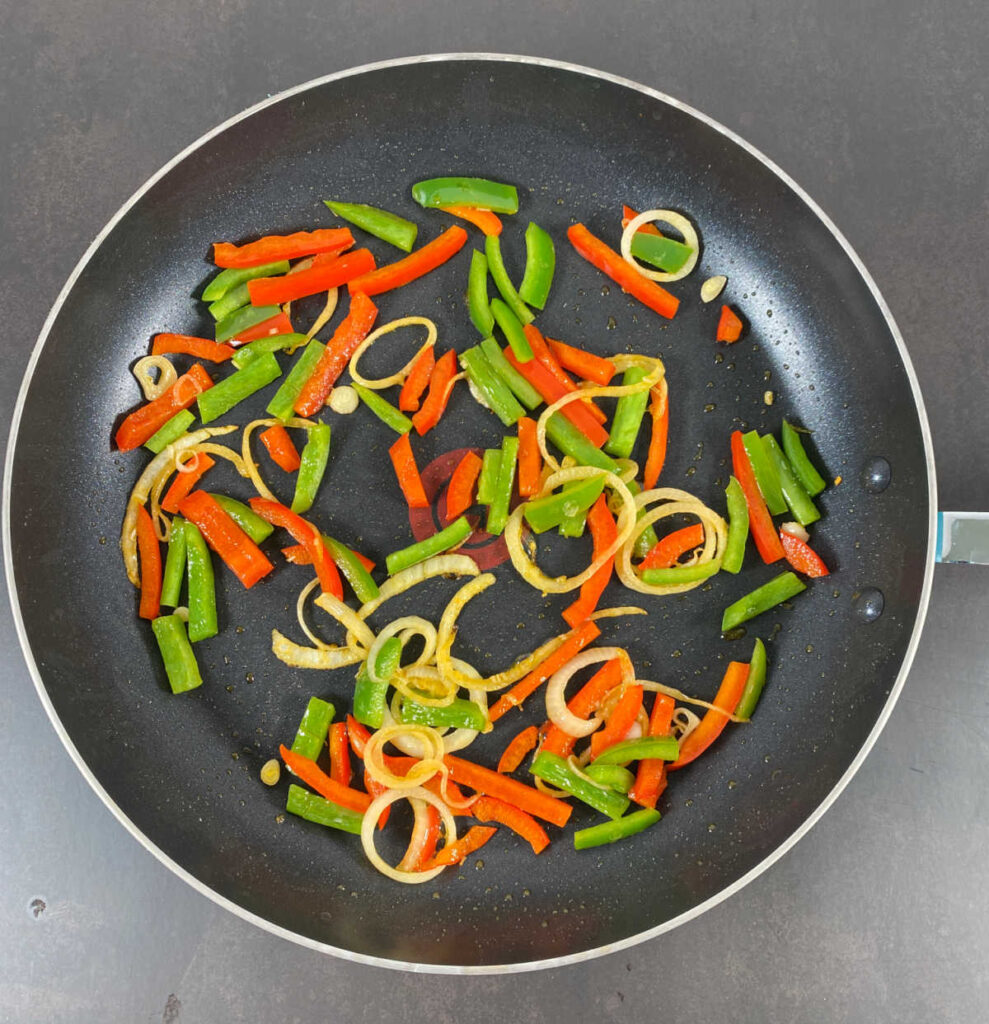 Process shot - bell peppers and onions cooking in a skillet. 