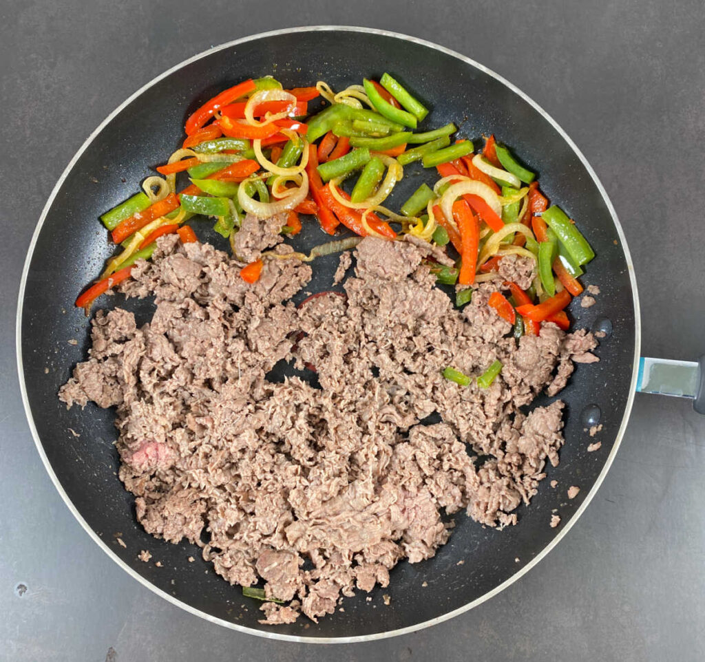 Process shot - cooked meat and vegetables in a skillet. 