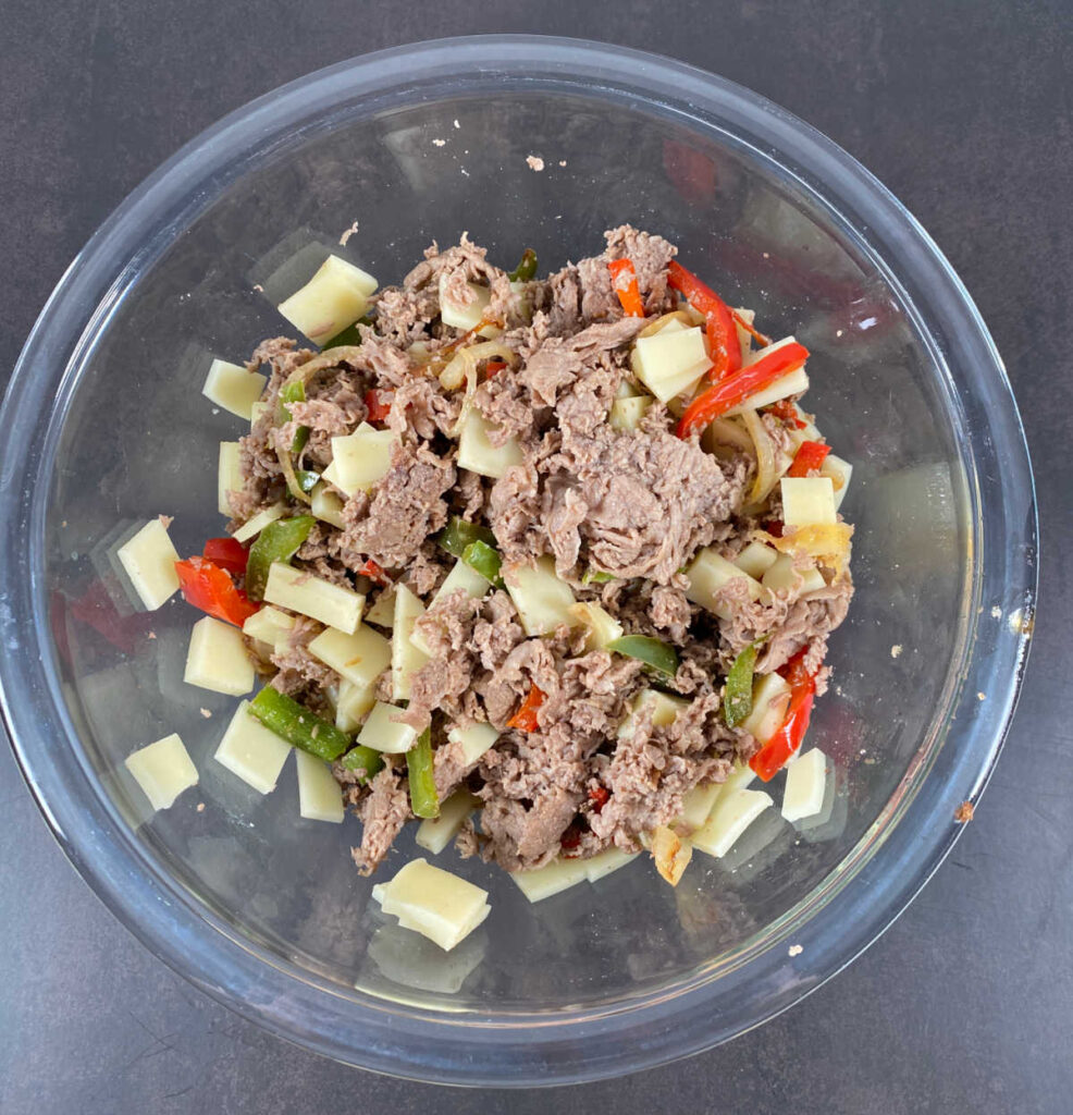 Process shot - meat, vegetables and cheese are mixed together in a bowl. 