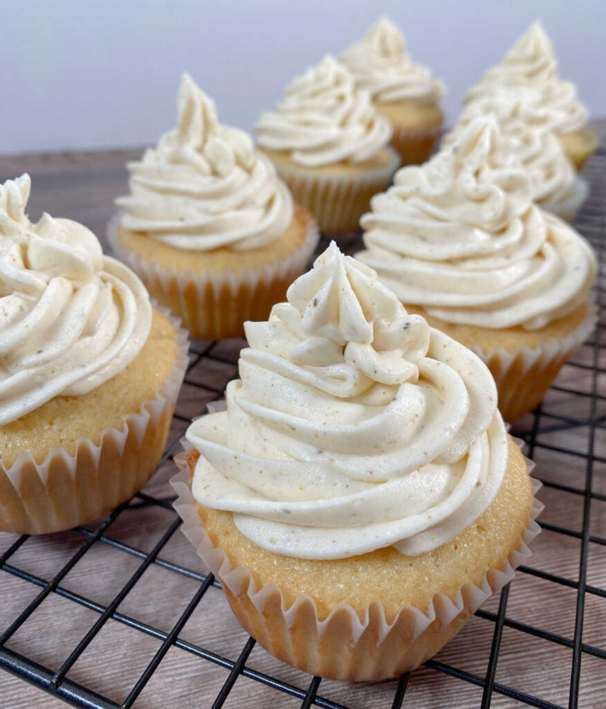 Close up image of frosted cupcakes on a wire rack, showing the Old Bay seasoning mixed into the frosting. 