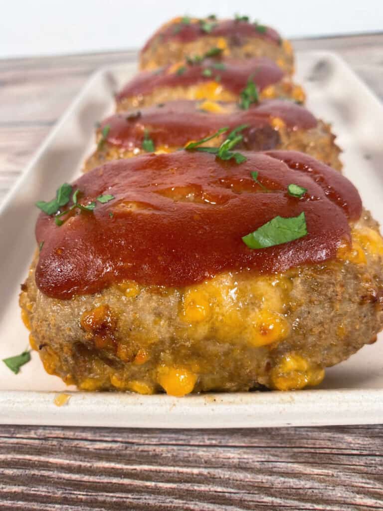 Tray of baked meatloaves in a row, sprinkled with parsley on top.