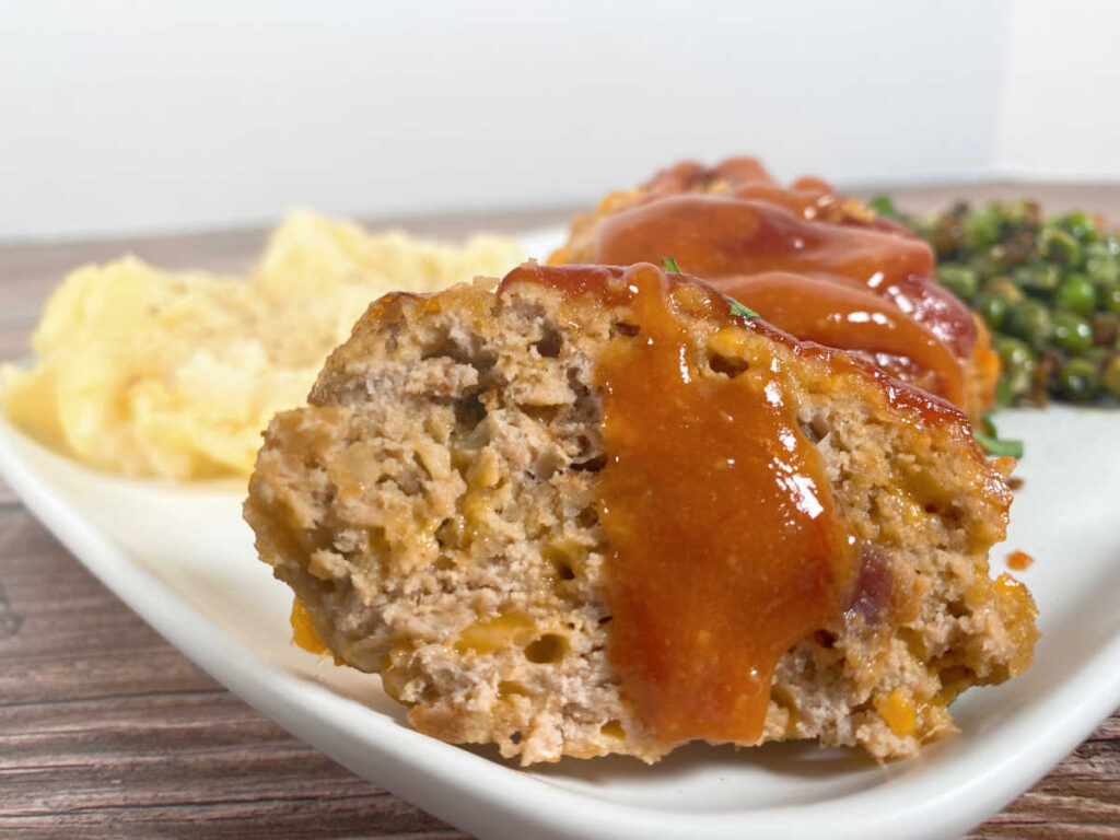 Close up image of sliced meatloaf with the glaze dripping down the meat. 