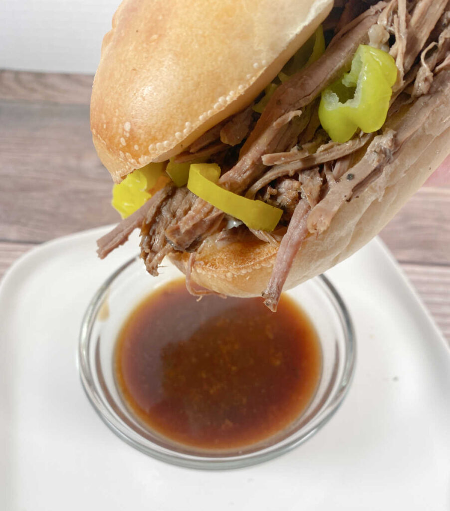 Sandwich hovers above a bowl of gravy waiting to be dipped. 