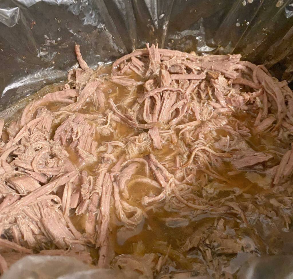 Process shot - cooked beef is shredded in the crock pot. 