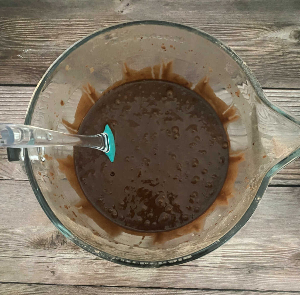 process shot - wet and dry ingredients are mixed together in a glass bowl. 