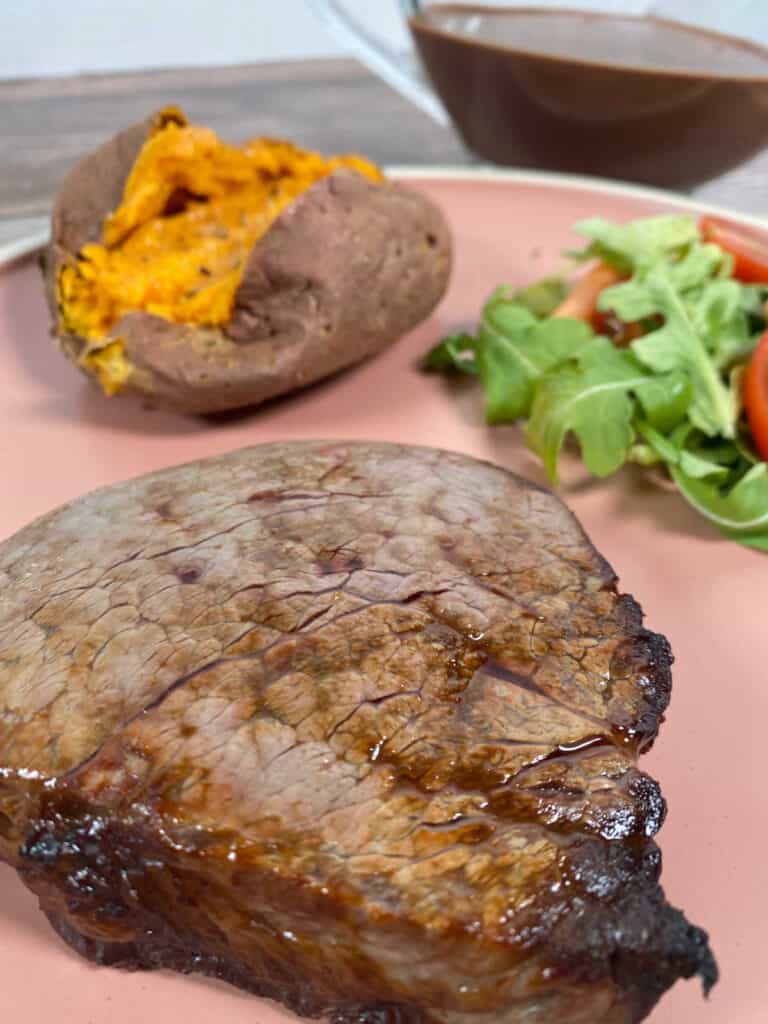 Close up of cooked steak with side dishes in the background. 