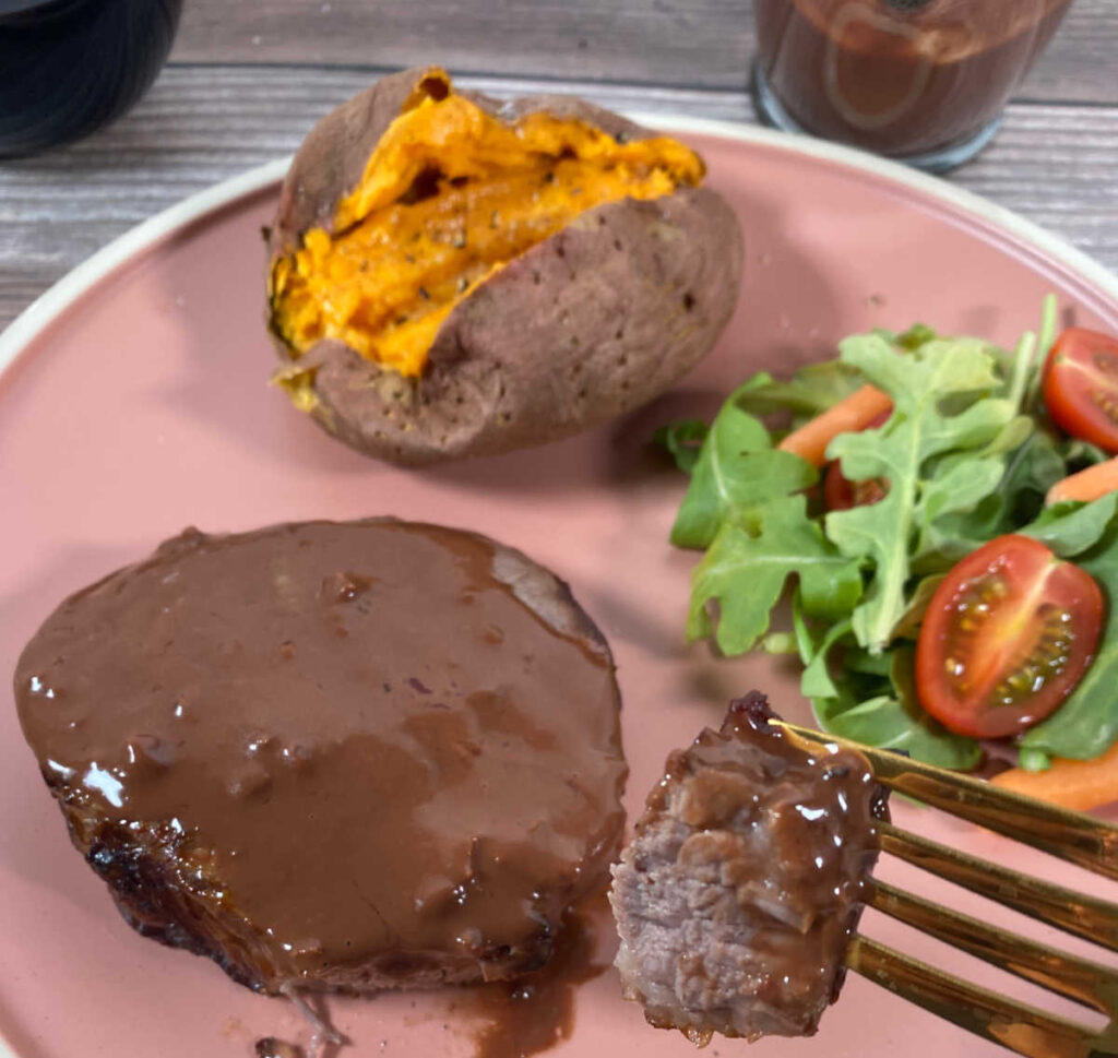 Bite of steak with sauce on fork. 