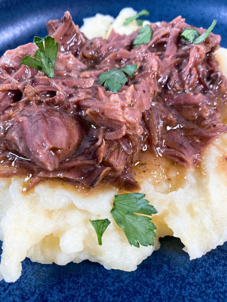 Close up image of the shredded beef on top of mashed potatoes. 