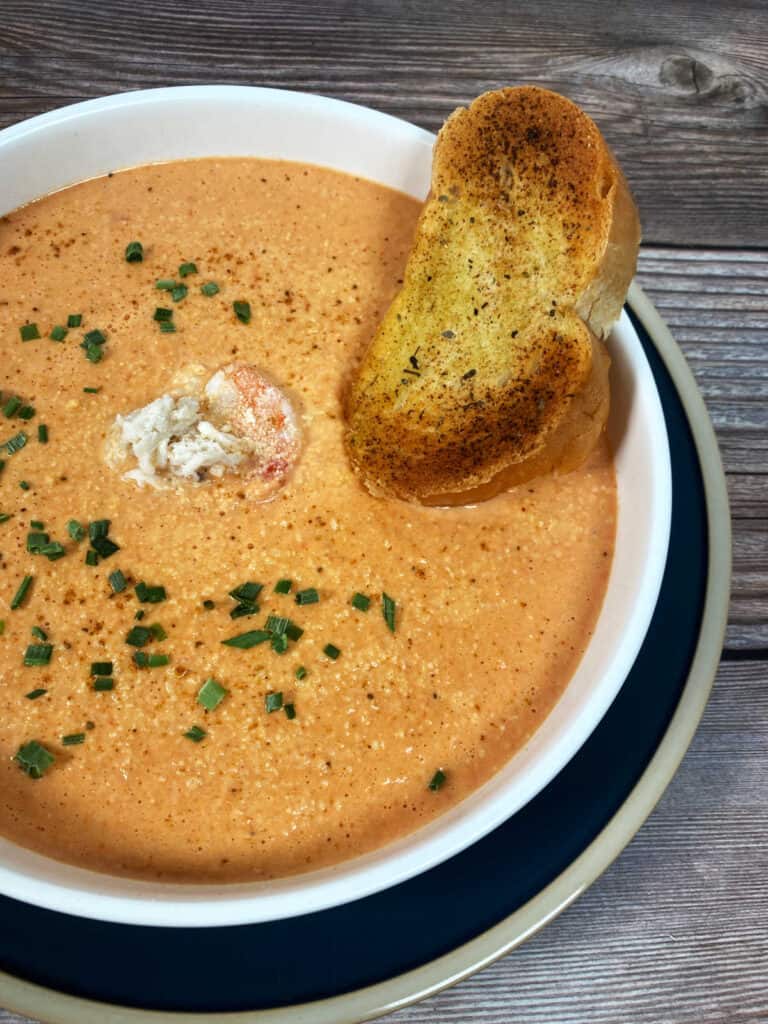 Close up image of soup showing the garnishes - shrimp and chives. 