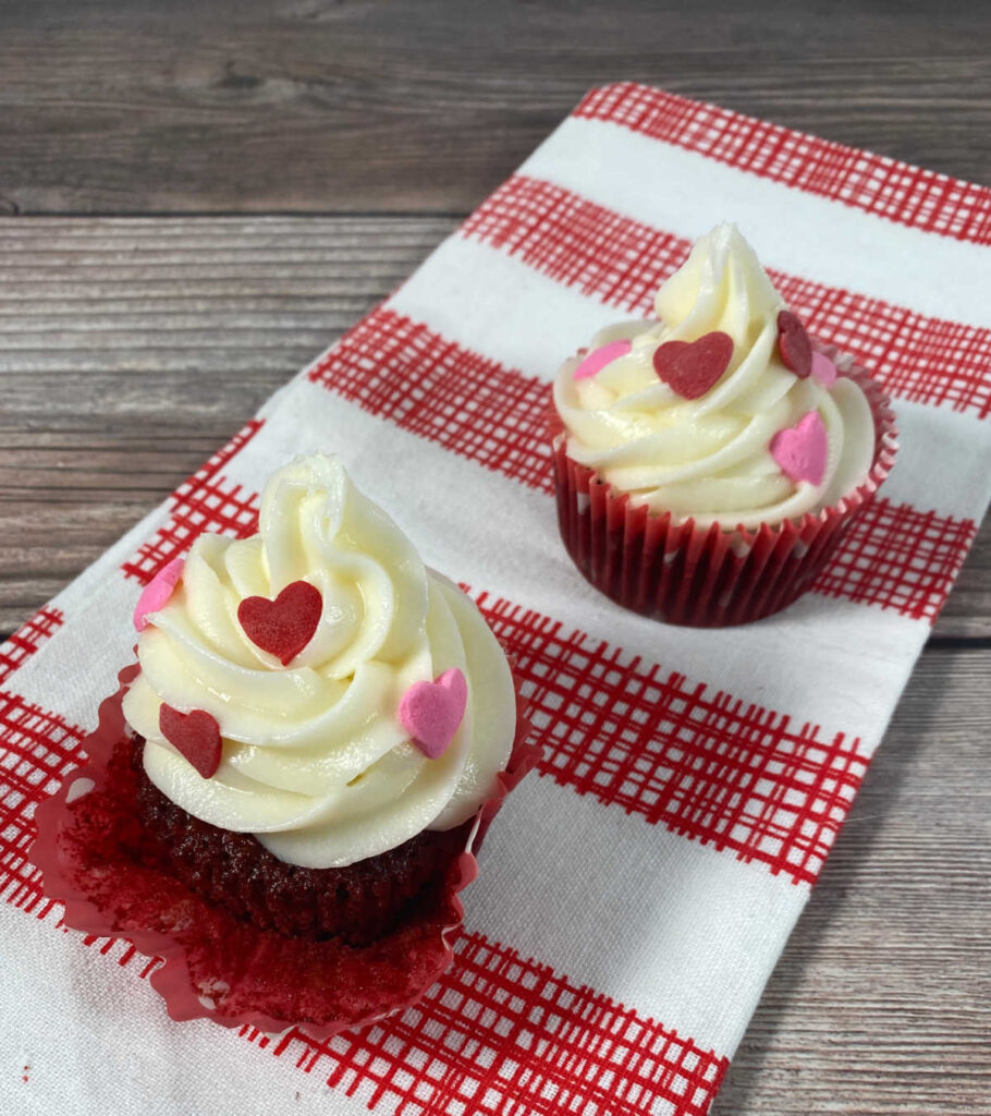 cupcakes decorated with heart sprinkles on a red checkered napkin. 