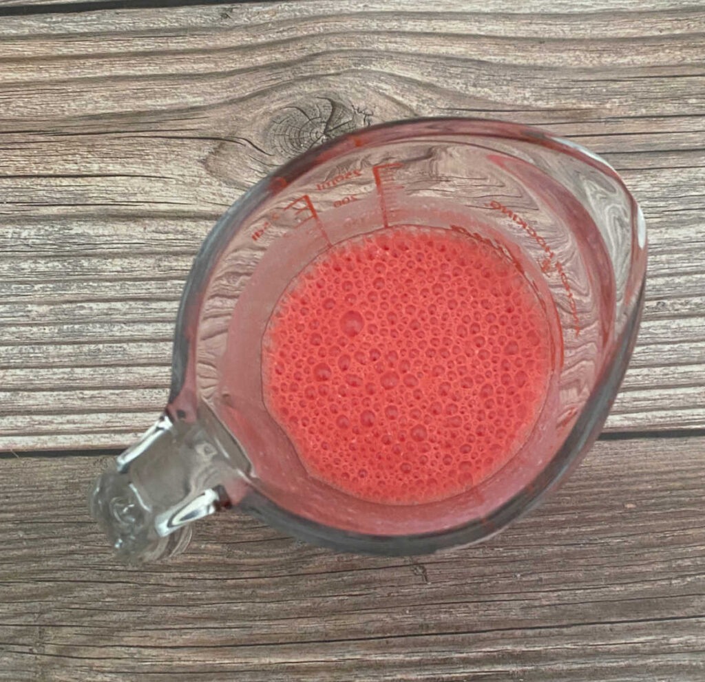 process shot - measuring cup of buttermilk and red food coloring 