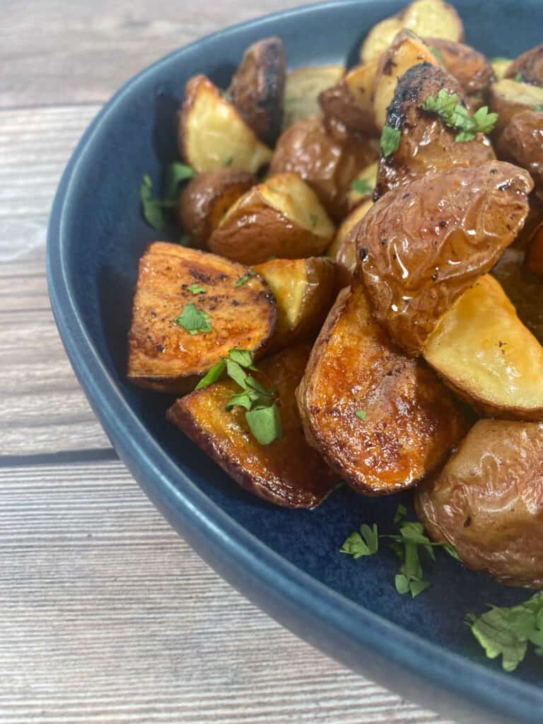 Crispy potatoes piled up in a navy blue bowl. 