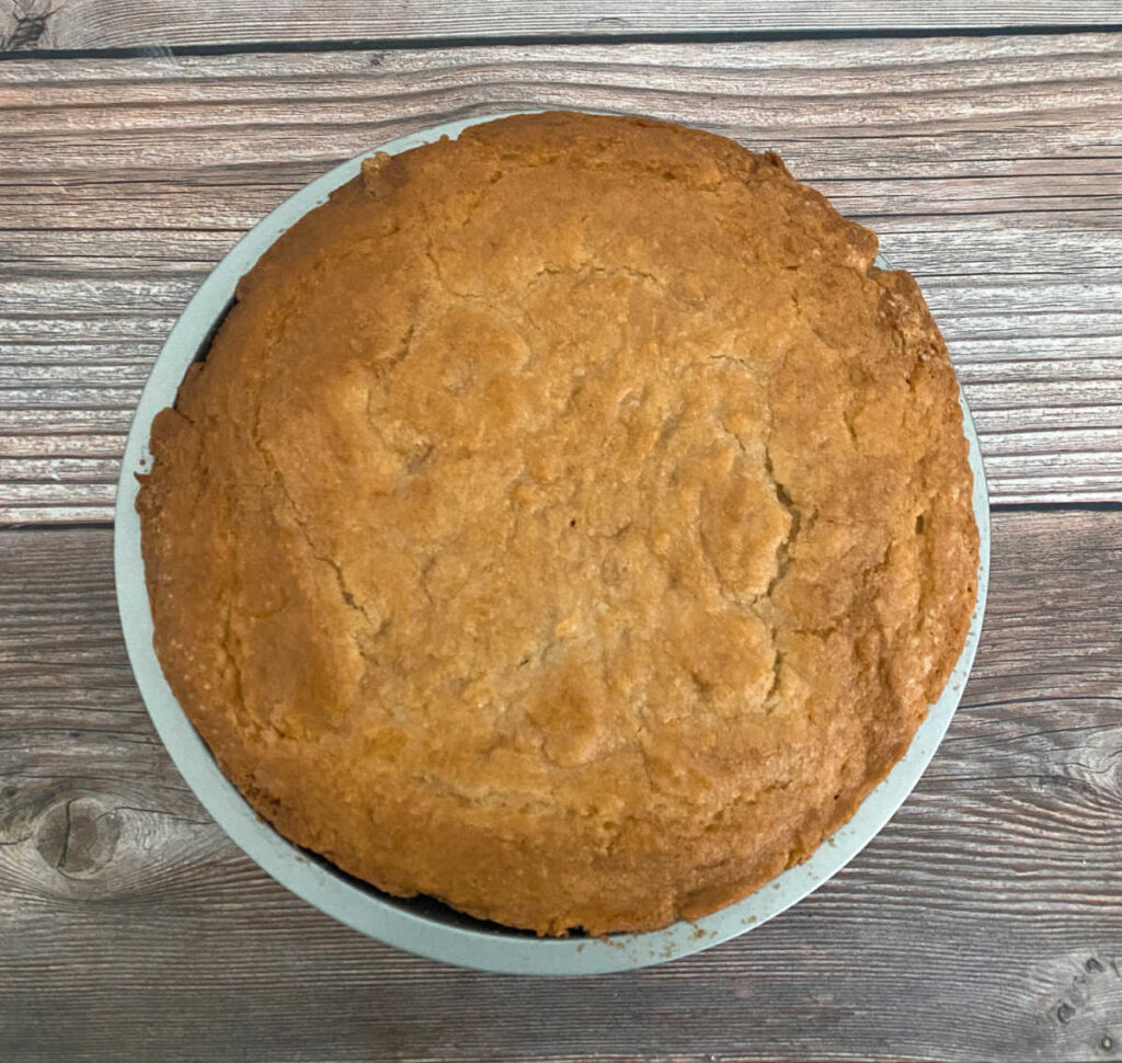 Process shot - unglazed, baked cake sits on a wooden background. 