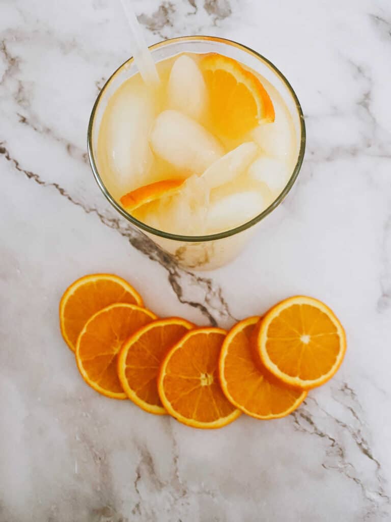 overhead image of the cocktail on a marble background surrounded by orange wedges. 