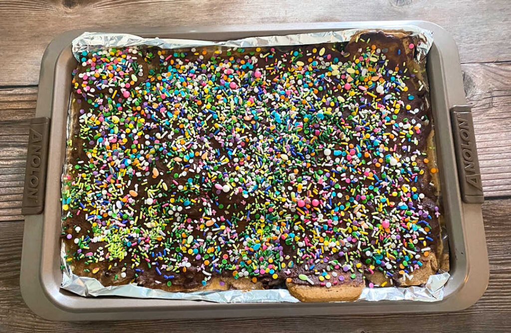 Baking tray of Easter Candy Crack Bars sits on a wooden background. 