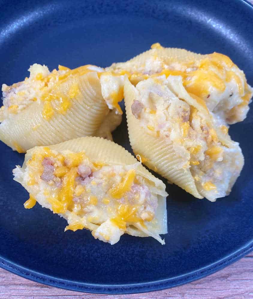 Four stuffed shells arranged on a navy blue plate. 