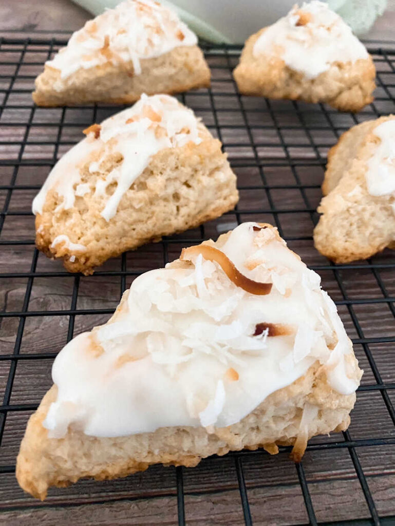 Close up image of scones with toasted coconut on top, sitting on a wire rack. 