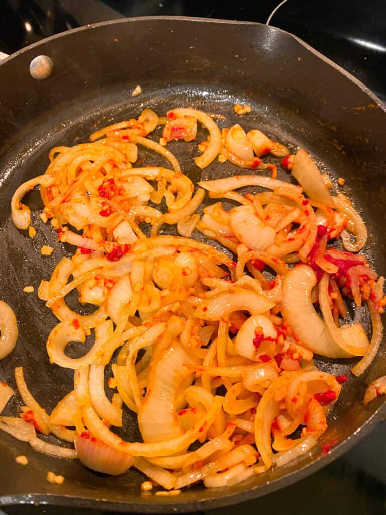 Process shot - onions, garlic and tomato paste in a skillet. 