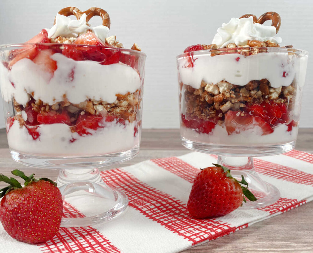 Two parfaits in mini trifle cups, sitting on a red and white printed towel. 