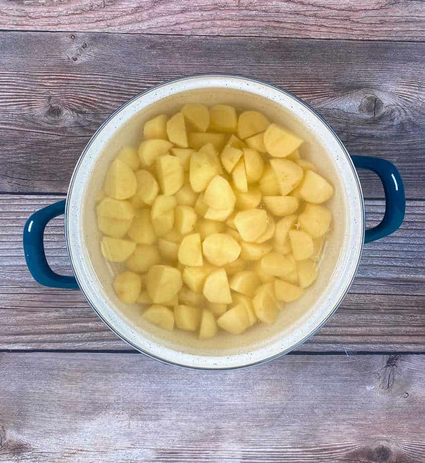 prep image - boiled potatoes in a pot on a wooden background. 