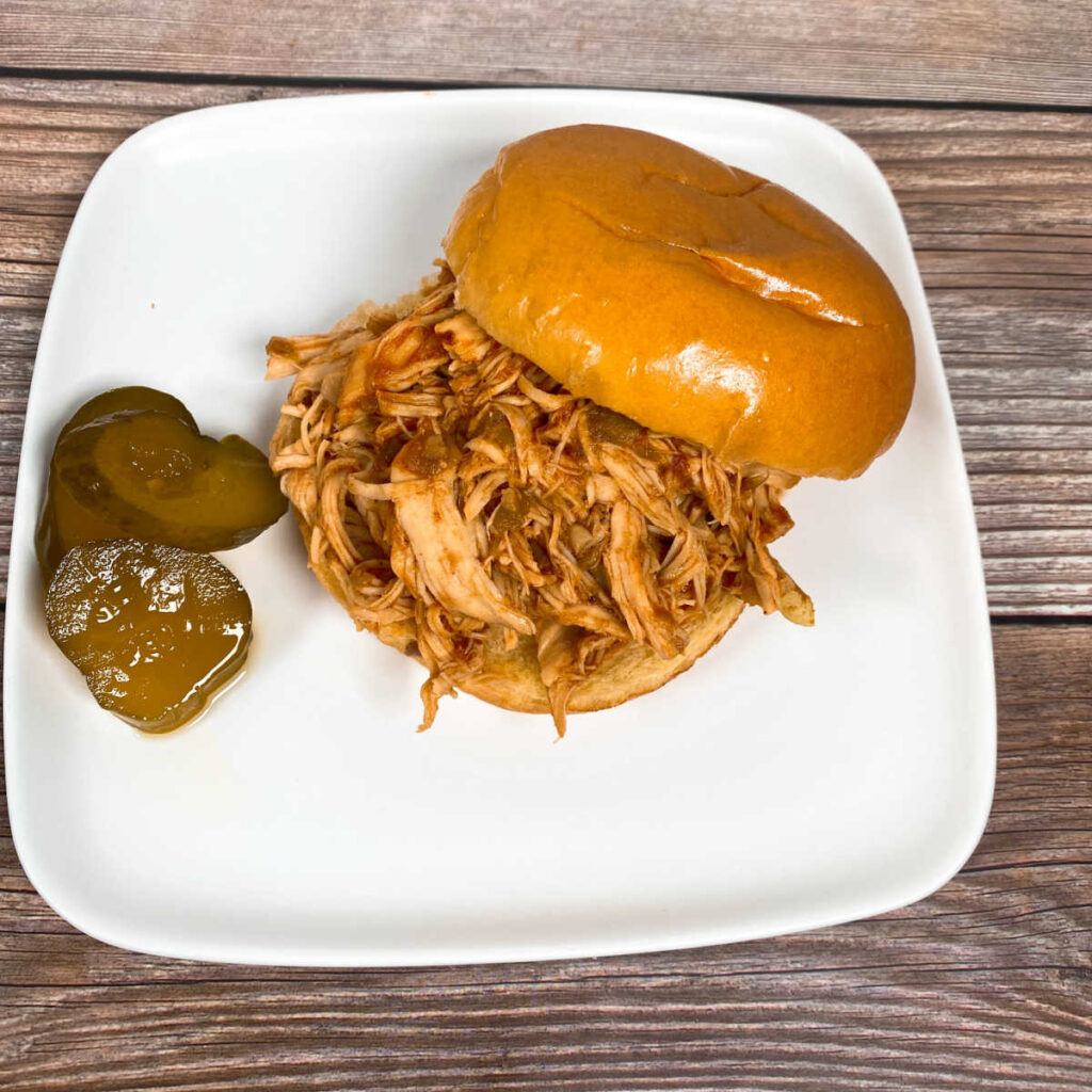 sandwich with pickles sits on a white plate. 