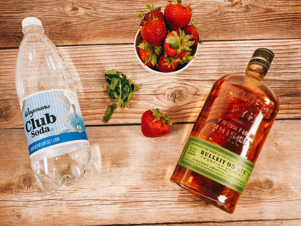 ingredients for the cocktail sit on a wooden background. 