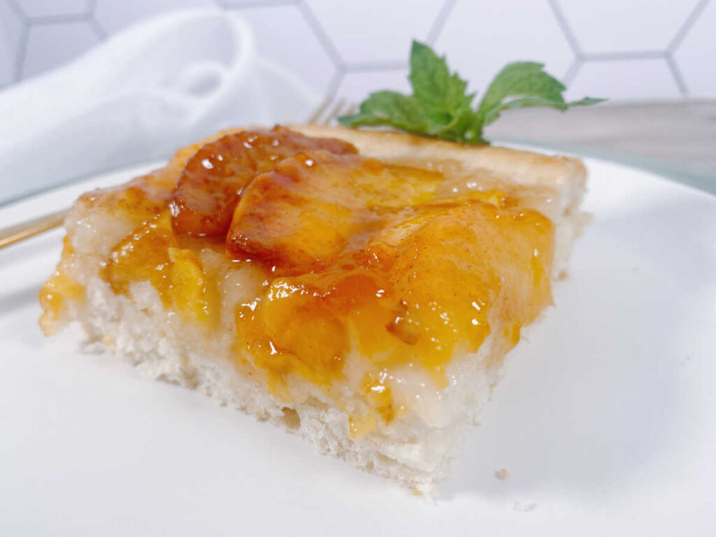 cake sits on a white square plate, garnished with fresh mint.