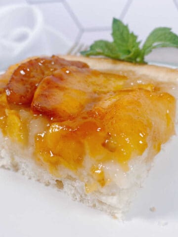 cake sits on a white square plate, garnished with fresh mint.