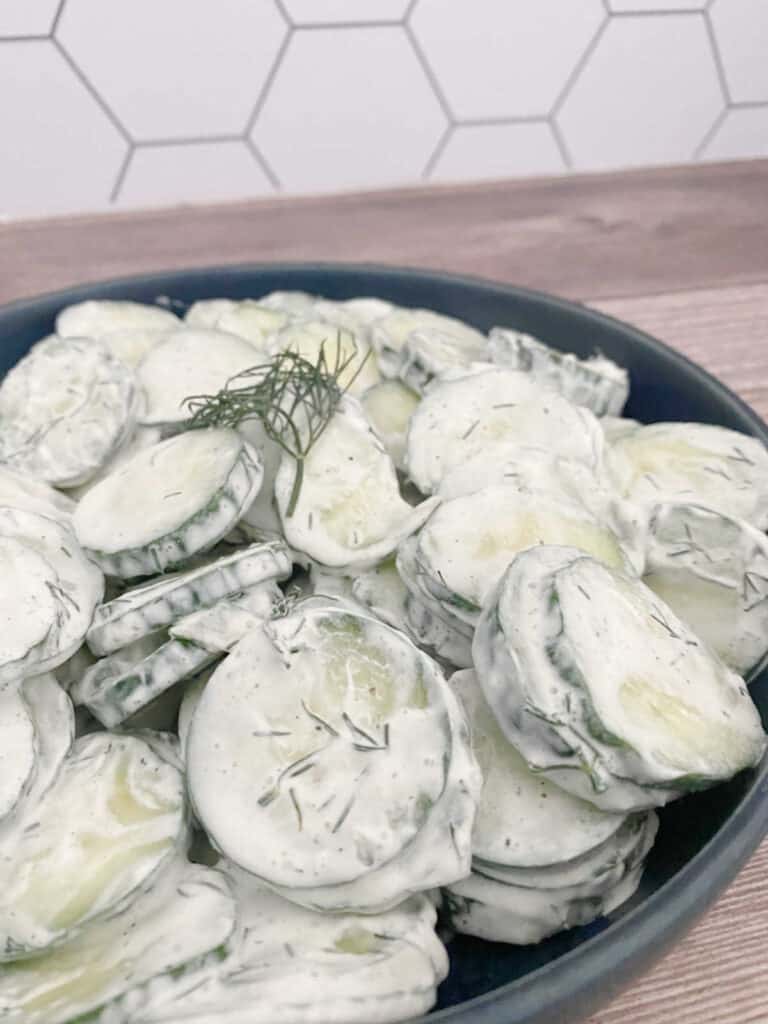 Close up image of the salad in a dark blue bowl on a wooden background.