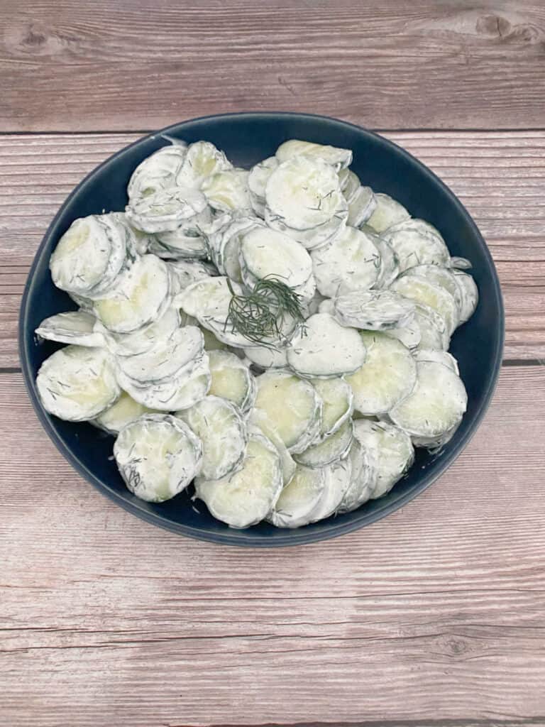 salad sits in a dark blue bowl on a wooden background. 