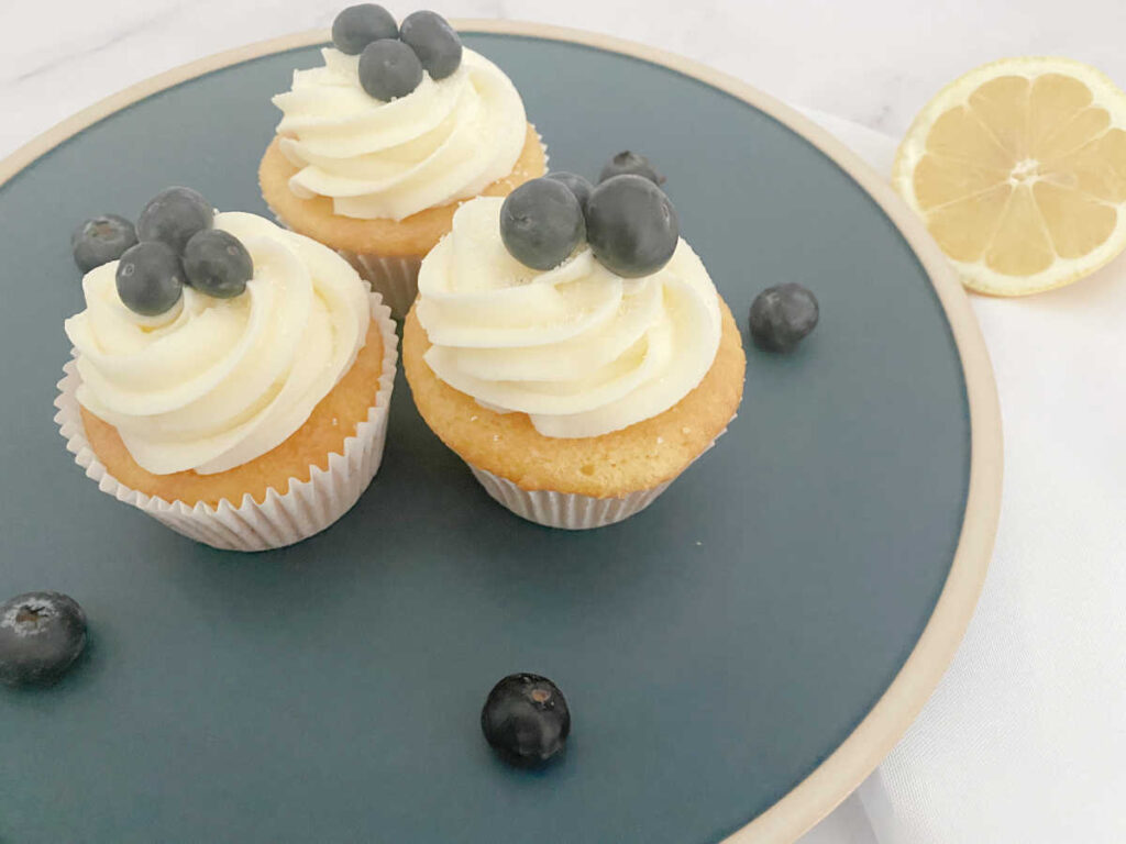 Cupcakes sit on a dark blue plate. 