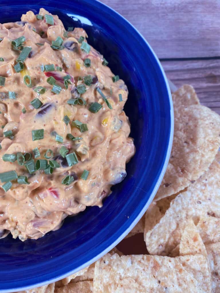 Close up image of dip in a blue bowl, garnished with chives.