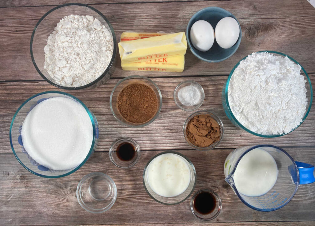 Ingredients for the cake sit on a wooden background. 