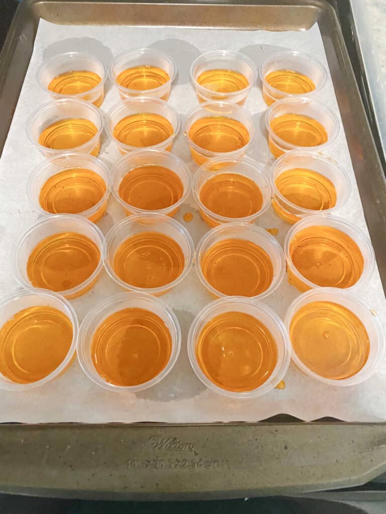 Jello shots in single layers on a parchment lined sheet pan.