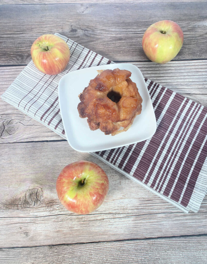 Overhead image of dessert on a white plate surrounded by apples.