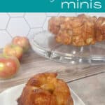 Monkeybread sits on a white plate surrounded by apples and desserts on a glass cake stand.