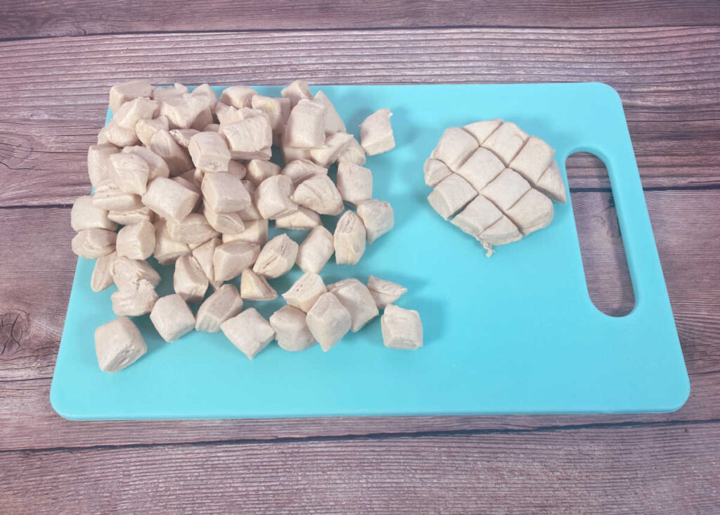 Process shot - biscuits cut into pieces on a blue cutting board. 