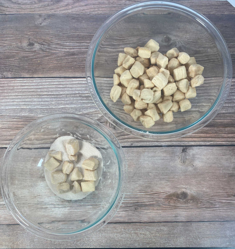 Process shot - bowl of biscuit pieces tossed in cinnamon sugar. 