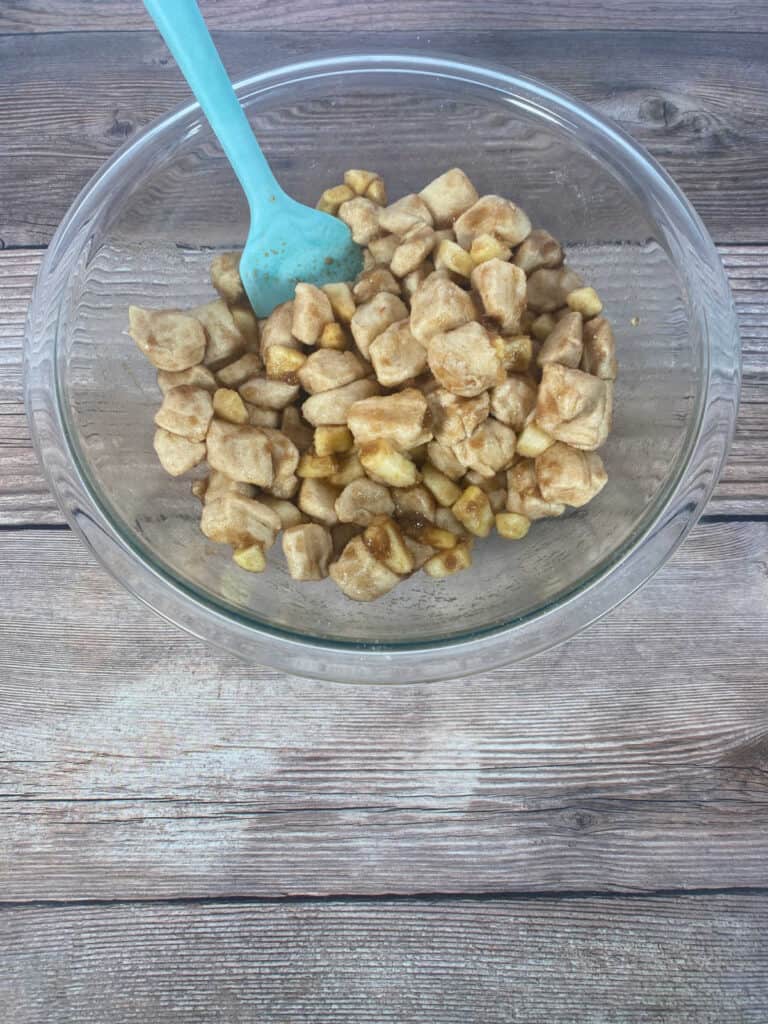 Process shot - apples and biscuits tossed together in a glass bowl. 