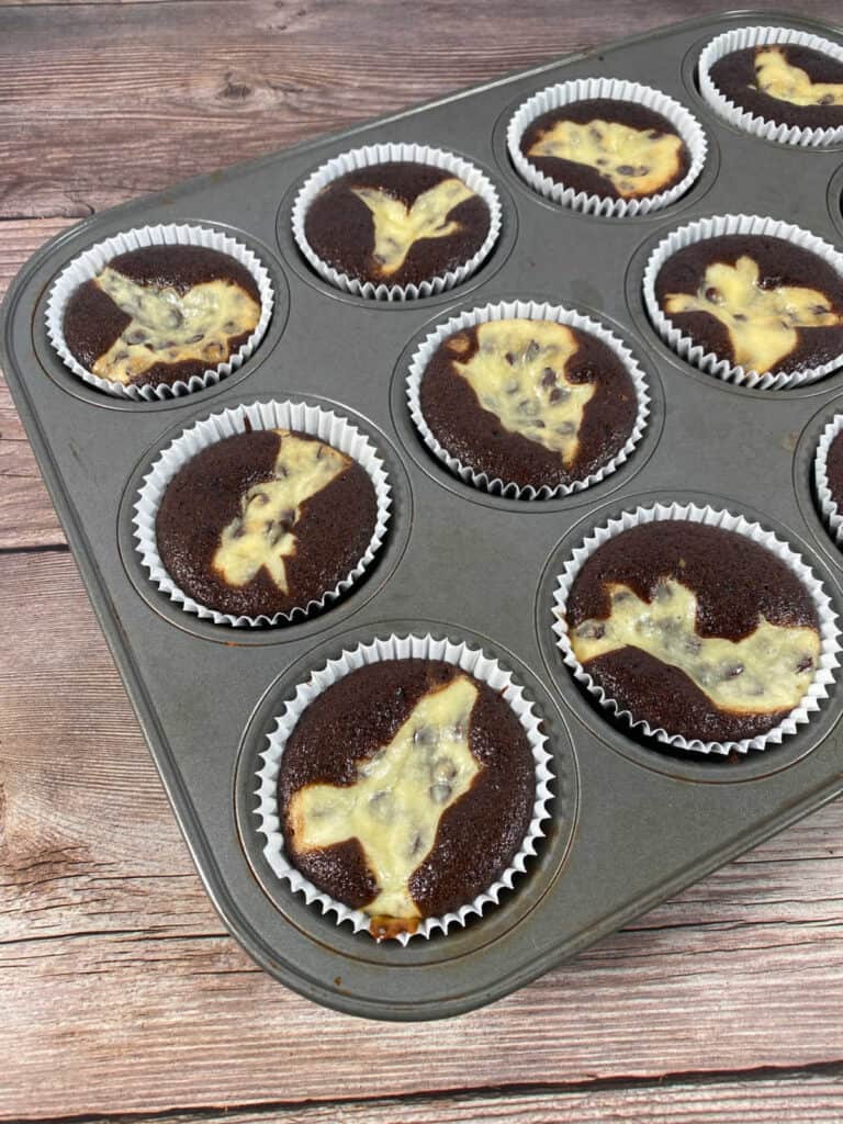 cupcakes sit in a pan on a wooden background. 