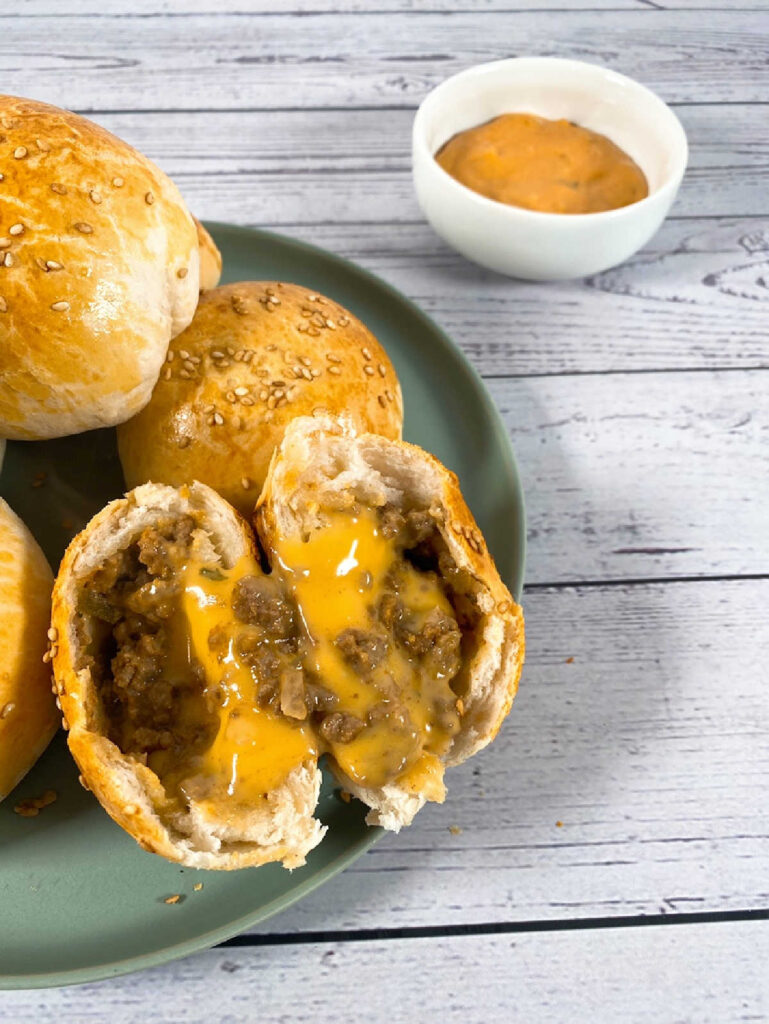 close up of cheese oozing out of a sliced cheeseburger bomb.