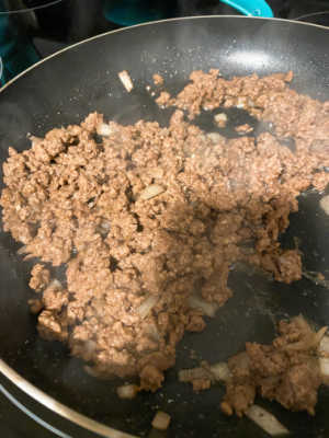 Process shot - ground beef and onions cooking in a skillet. 