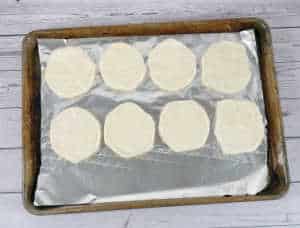 Process shot - flatten biscuits on a lined baking sheet. 